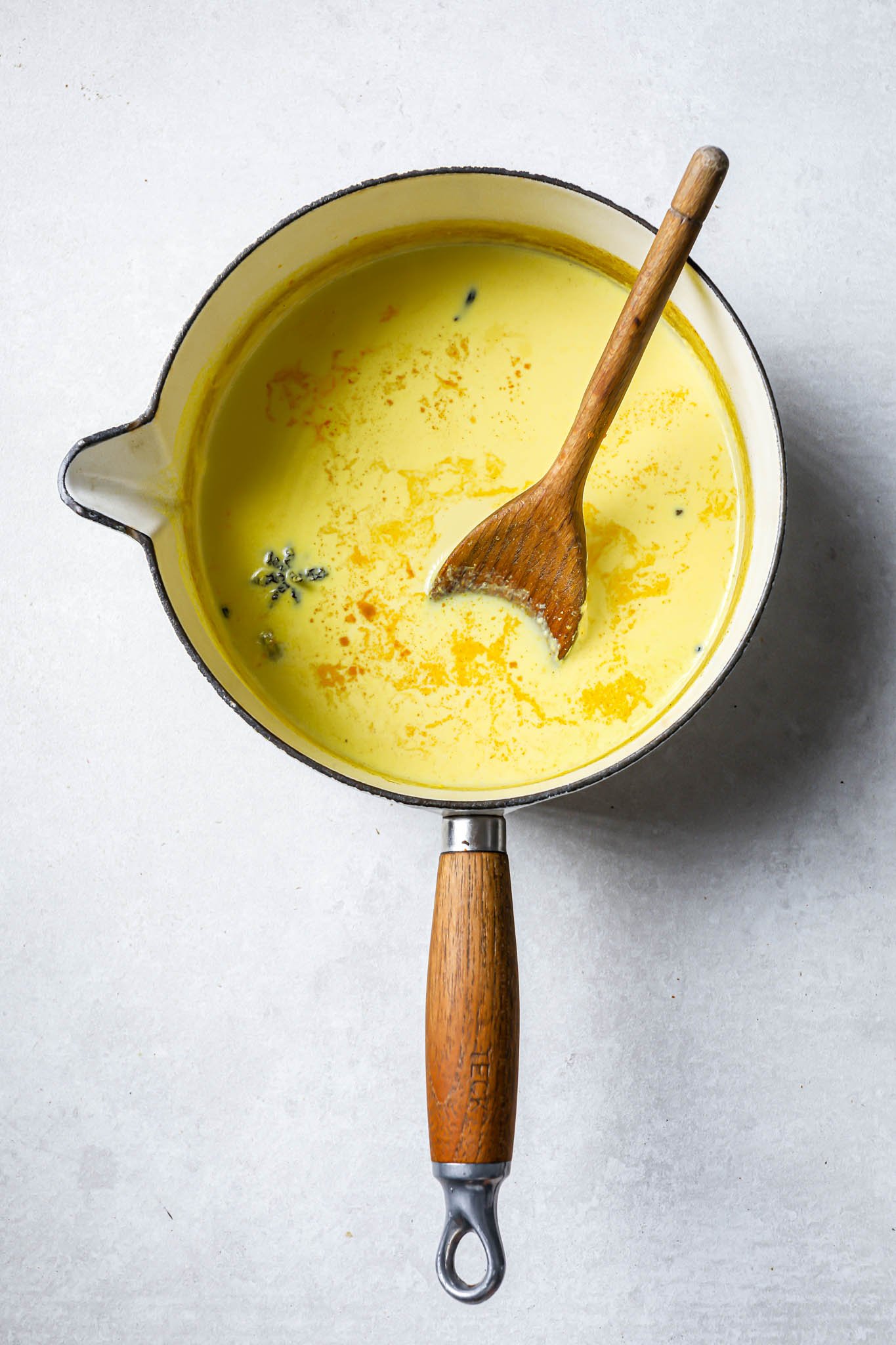 Mixing golden milk ingredients with a wooden spoon.