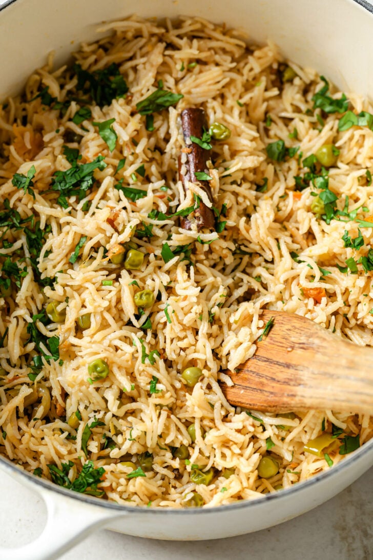 Closeup of cooked Matar Pulao in a dutch oven garnished with cilantro.