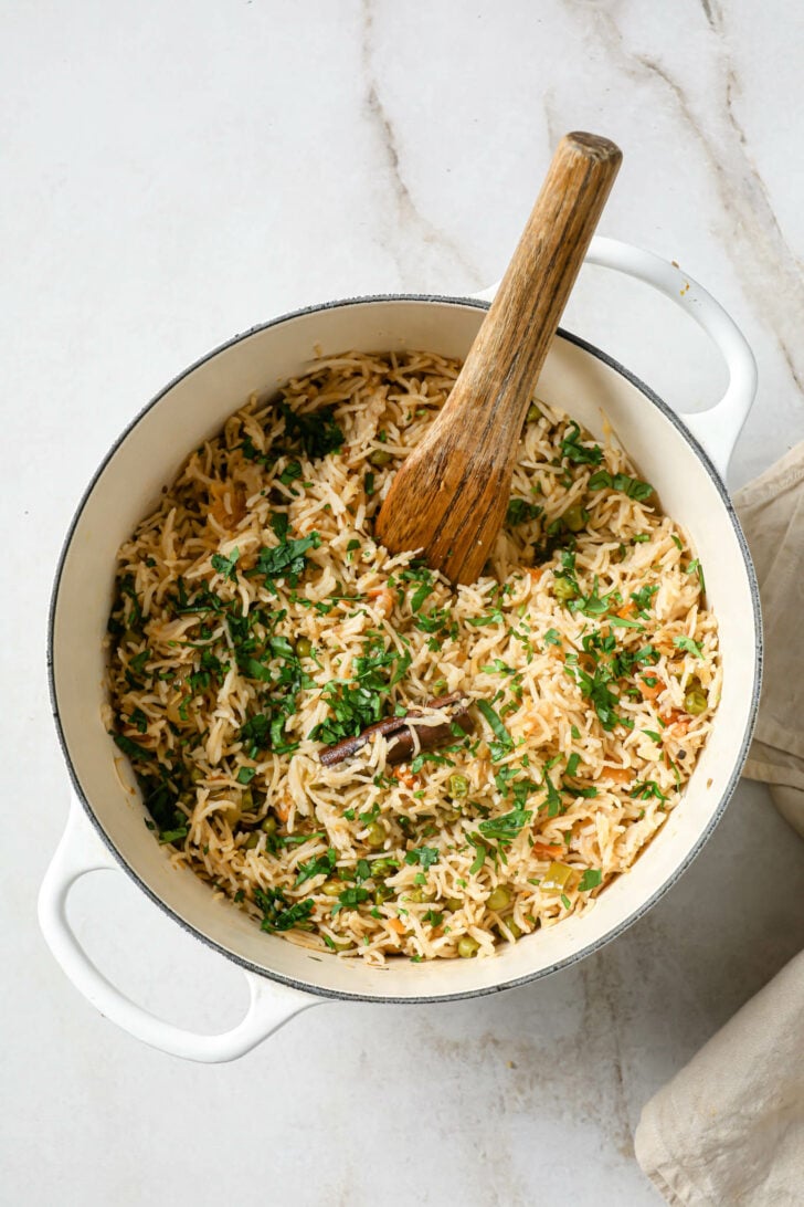 Cooked Matar Pulao in a dutch oven garnished with cilantro.