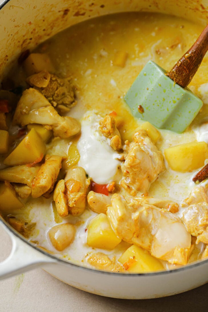 Coconut milk added to dutch oven with chicken curry.
