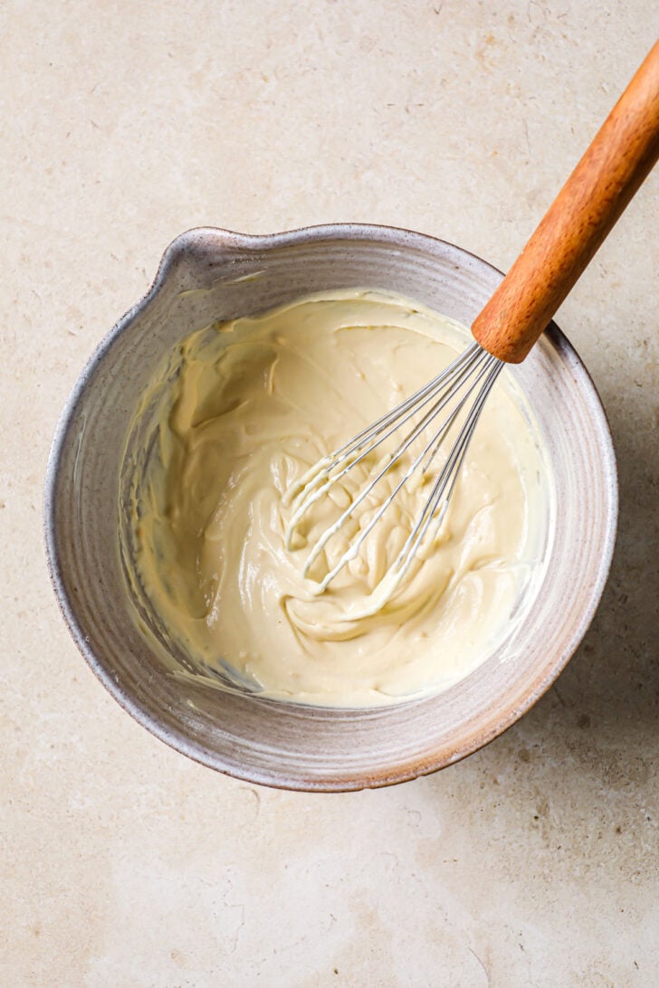 Yogurt and gram flour whisked together in a bowl.