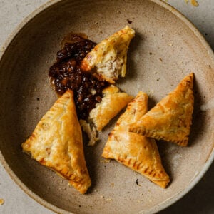 A bowl of partially eaten Chicken Puff Pastires with tamarind chutney.