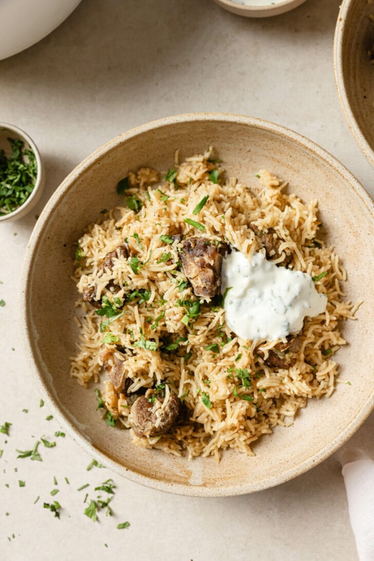 A bowl of Mutton Pulao with a dollop of raita.