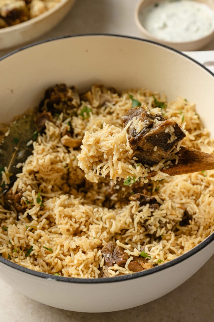 Holding a spoonful of Mutton Pulao over a pot.