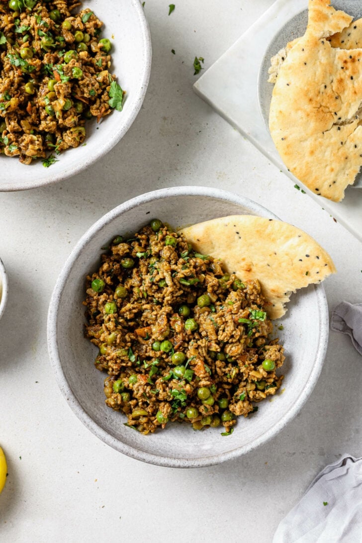 Keema Matar in a bowl with a piece of naan.