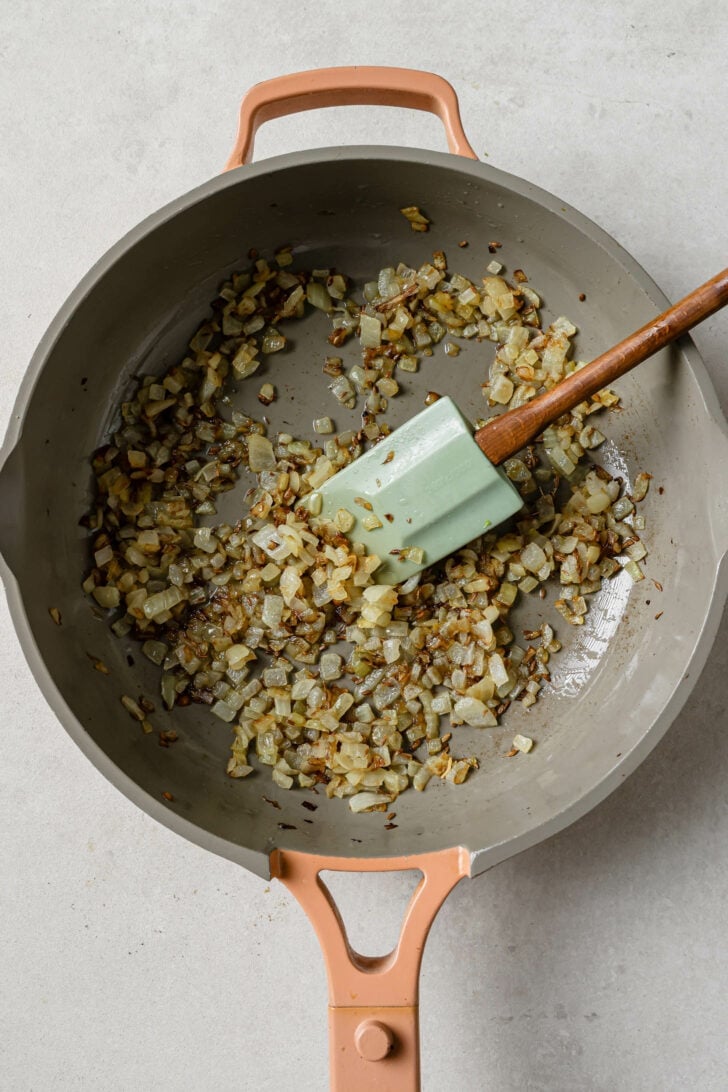 Sauteed onions and cumin seeds in a skillet for Keema Matar.