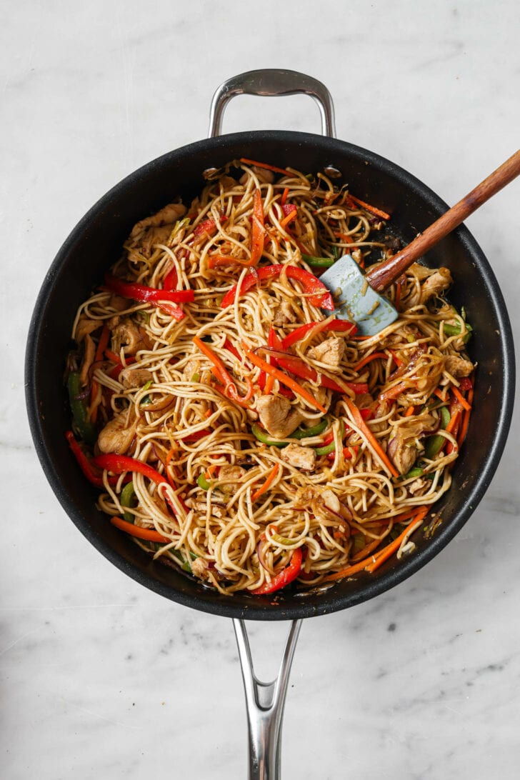 Noodles, sauce and stock added to skillet to make Hakka Noodles.