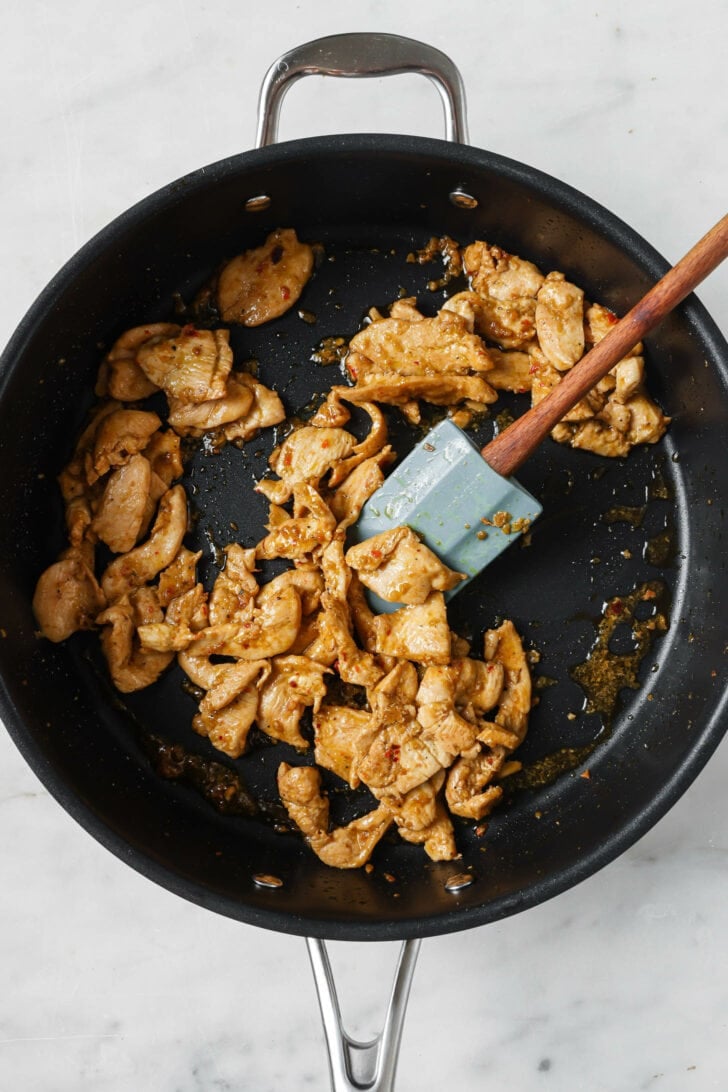 Stir fried chicken with ginger and garlic in a skillet to make Hakka Noodles.