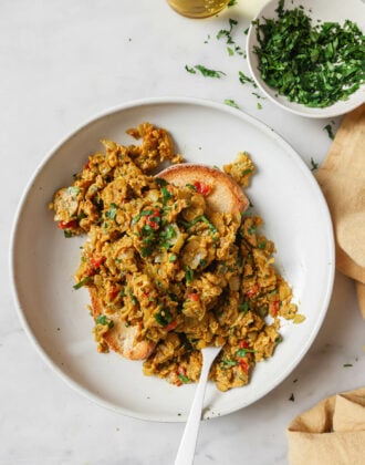 A plate of Egg Bhurji piled on top of a piece of toast garnished with cilantro.