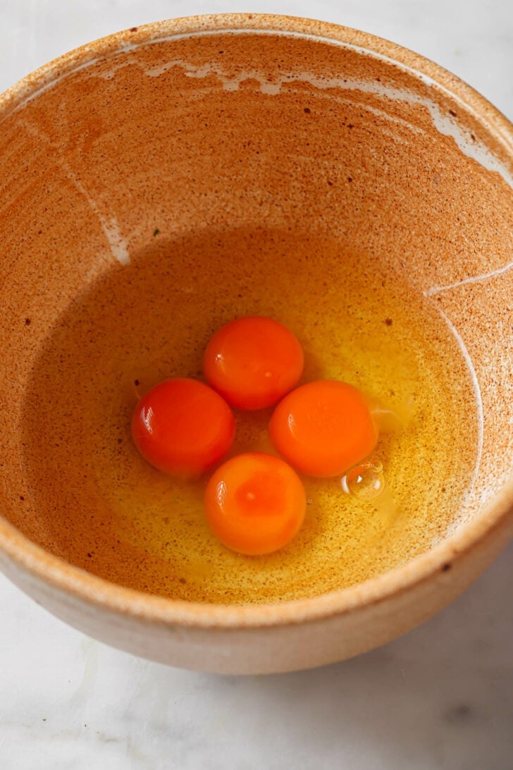 Four cracked eggs in a bowl to make Egg Bhurji.