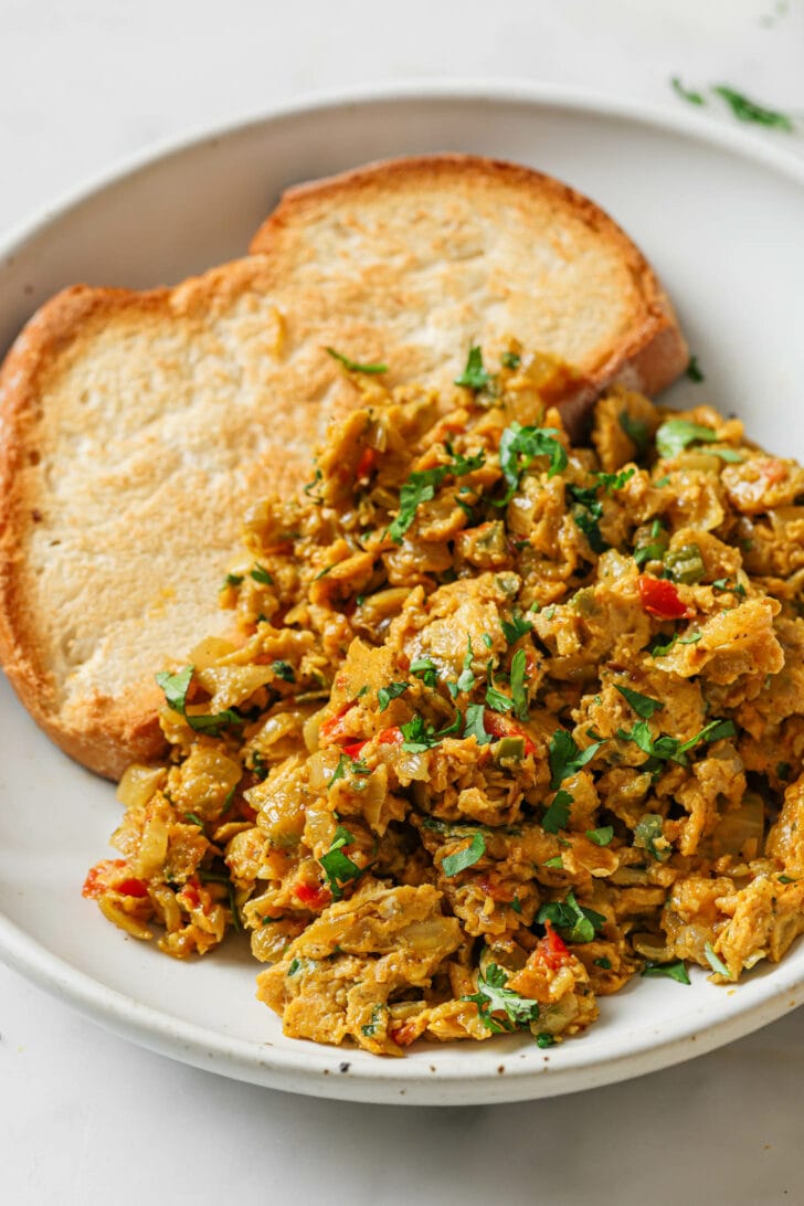 Close up of a plate of Egg Bhurji garnished with cilantro alongside a piece of toast.