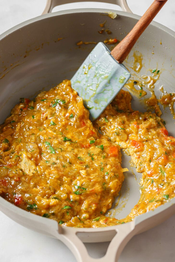 Cooking Egg Bhurji in a skillet with a rubber spatula.