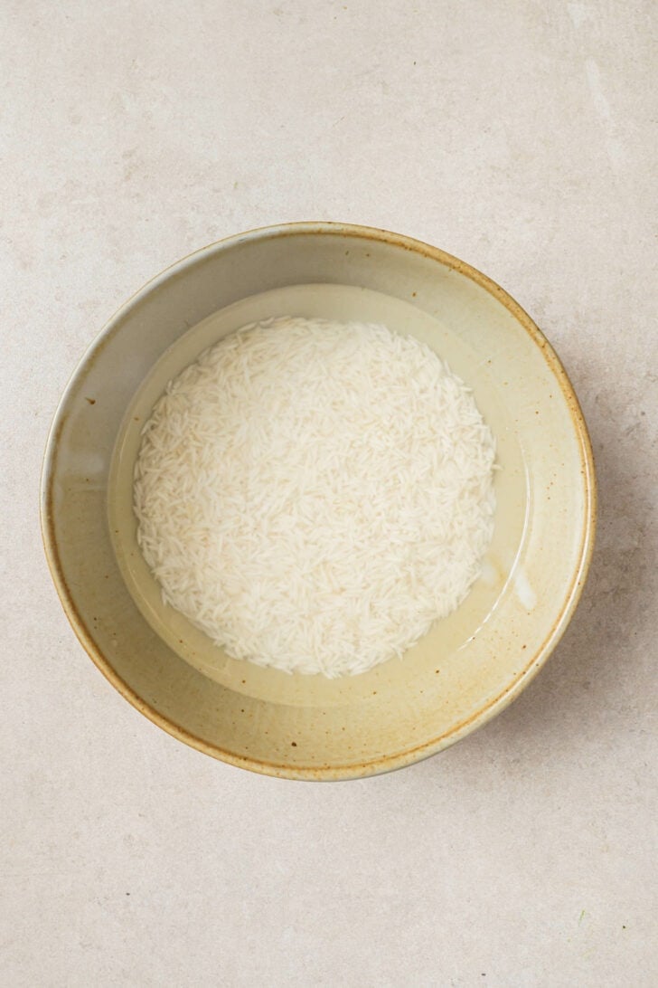 Basmati rice soaked in water in a bowl.
