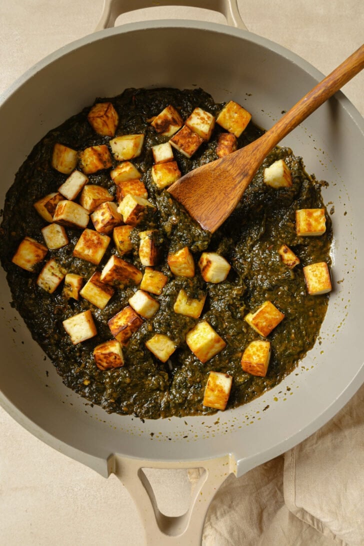 Pan seared paneer added to pot with pureed spinach and tomato mixture.