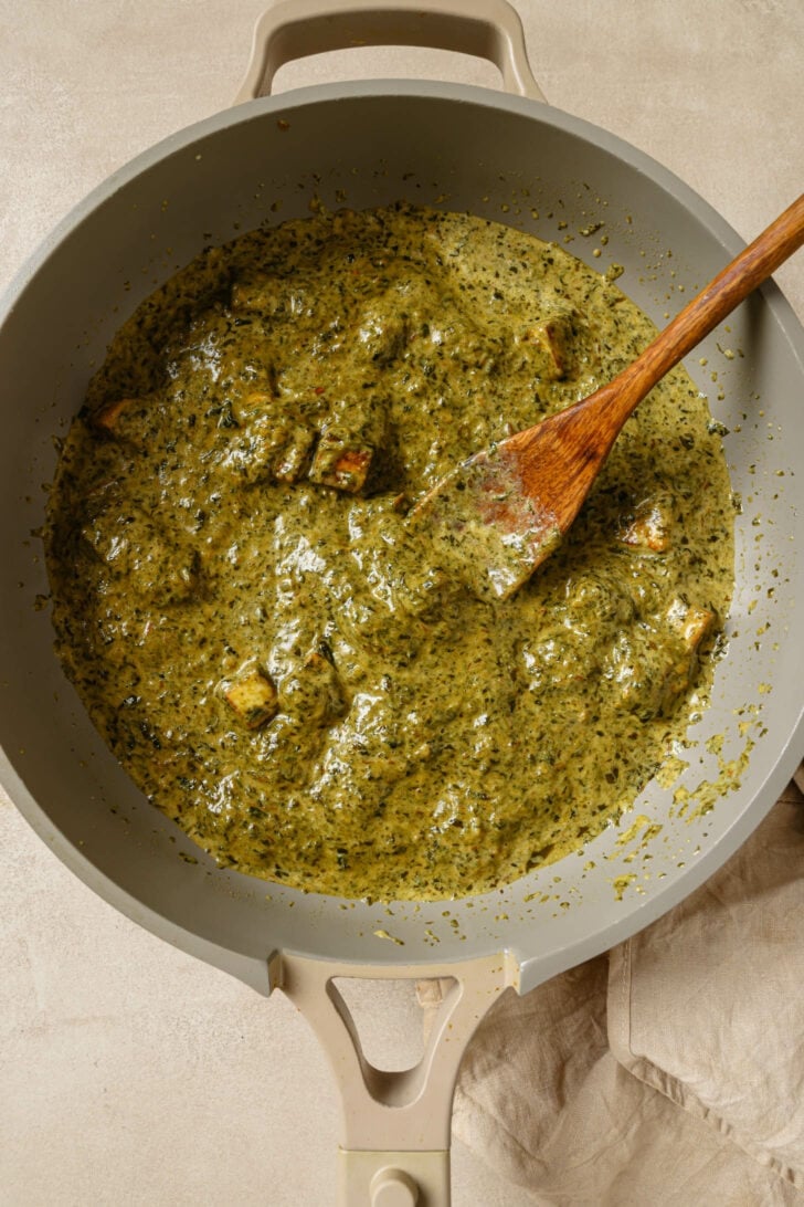 Palak Paneer in a pot with a wooden spoon.