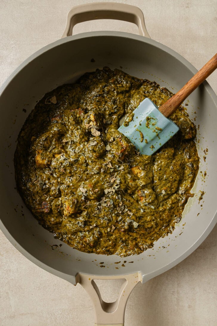 Close up top view of Palak Paneer in a pot with a rubber spatula.