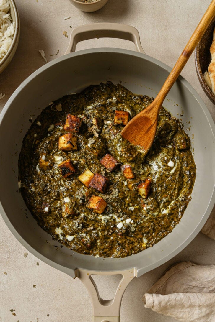 Top view of Palak Paneer in a pot with a wooden spoon.