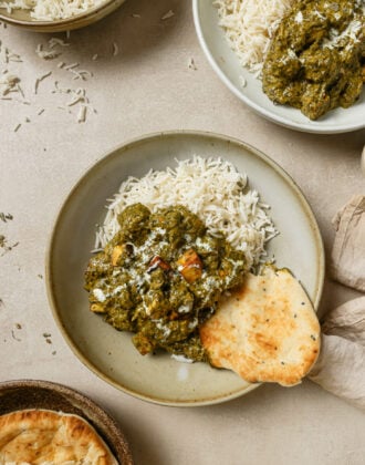 Palak Panner on a round plate with rice and naan.