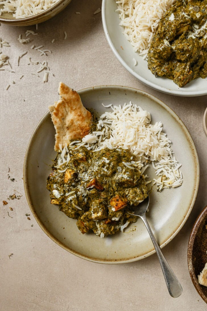 Partially eaten plate of Palak Paneer with rice and naan.