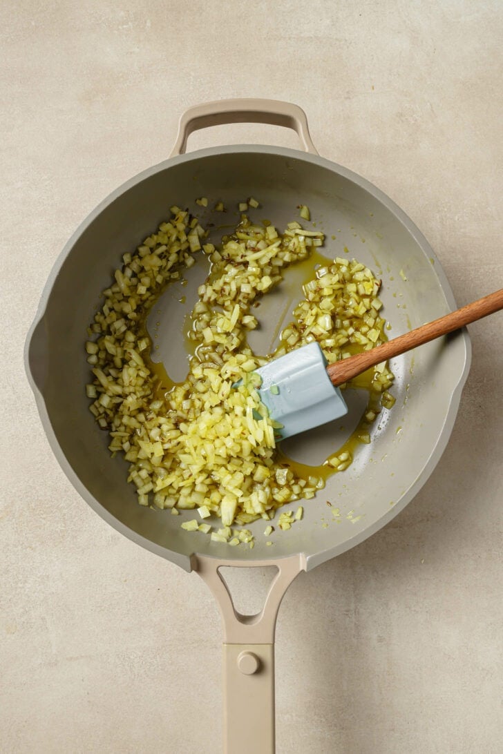 Sautéing onions in a pan with a rubber spatula.