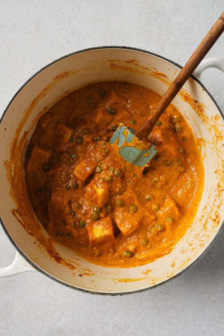 Matar Paneer in a dutch oven with a rubber spatula.