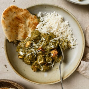 Palak Paneer in a bowl with naan and rice, ready to be eaten