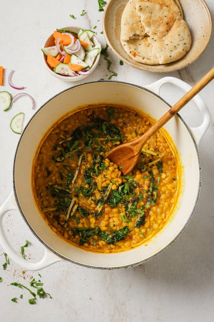 Chana Dal with tarka on top in a pot with a wooden spoon.
