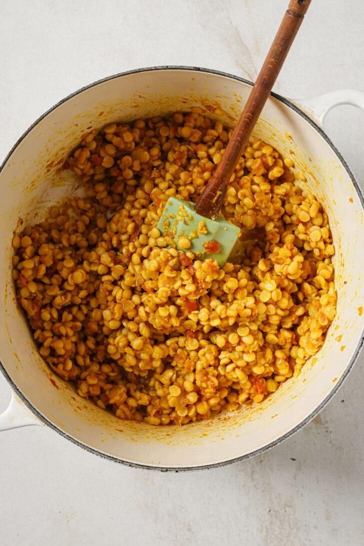 Chana Dal and masala mixed together in a pot with a rubber spatula.