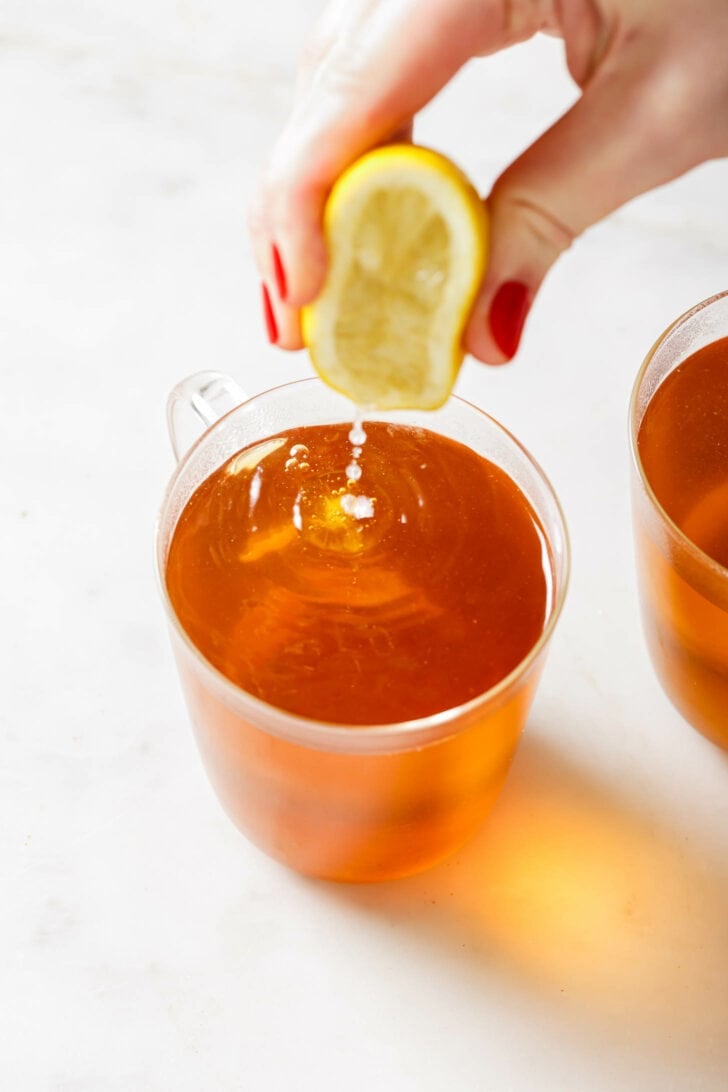 Squeezing lemon into a mug with Turmeric Tea.