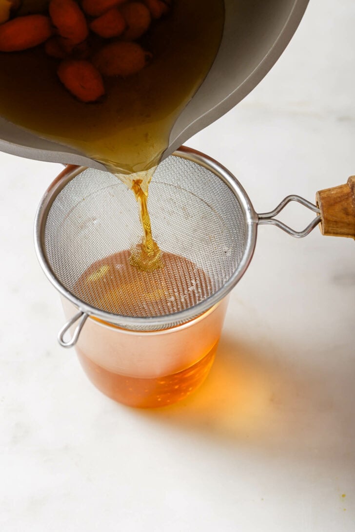 Straining Turmeric Tea into a glass.