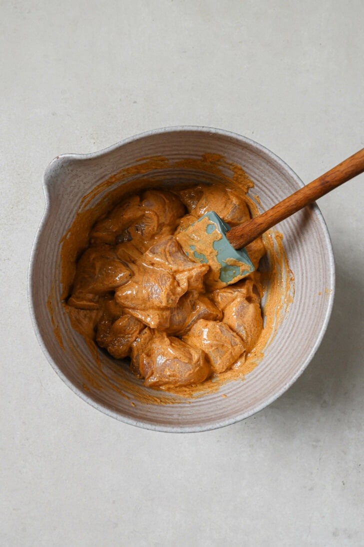 Chicken marinating in a grey bowl to make Butter Chicken.