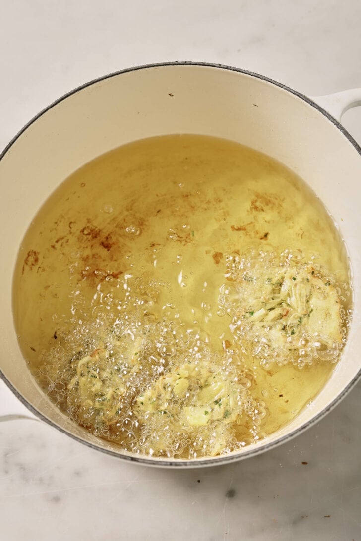 Adding pakoras to hot oil to fry.