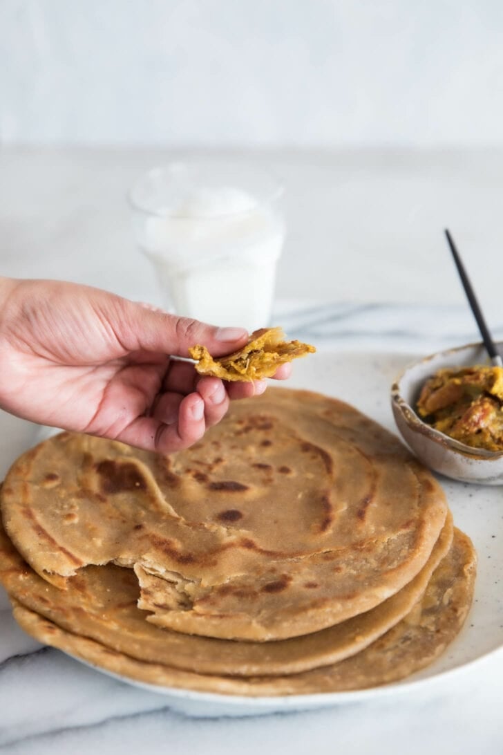 Holding a morsel of paratha with achaar ready to eat.